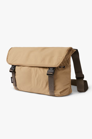 Sand-beige cinch messenger bag with top flap, side buckles, and adjustable shoulder strap