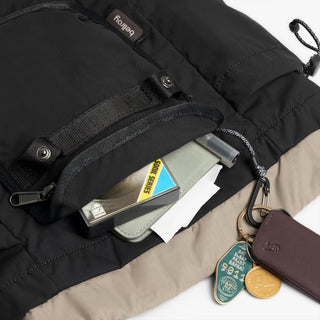 Black mini backpack close-up with front zip pocket, snap flap, and card slots