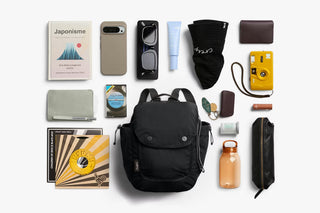 Black mini backpack laid out with accessories around it