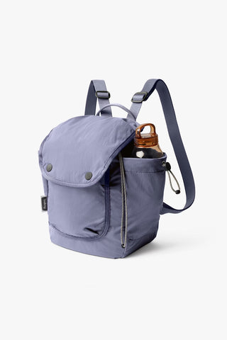 Lilac mini backpack with front flap pocket, shoulder strap, and side hanging bottle