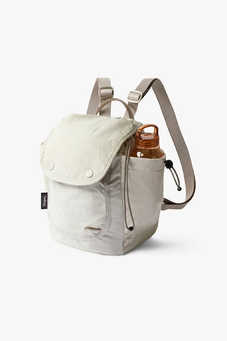 Bellroy cinch minipack backpack in oat, front flap and side carry strap visible
