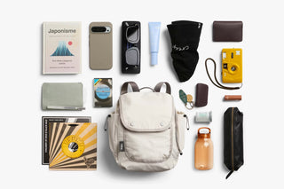 Bellroy cinch minipack backpack in oat shown with travel accessories and small gear items