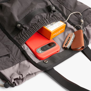 Bellroy cinch tote bag in charcoal, open top with phone and small leather pouch inside
