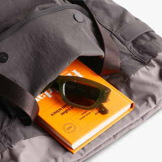 Bellroy cinch tote bag, charcoal fabric with snap top; interior holds sunglasses and books