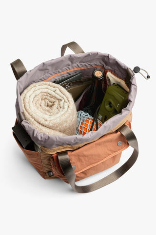Open tan cinch tote showing rolled towel, smartphone, and interior compartments