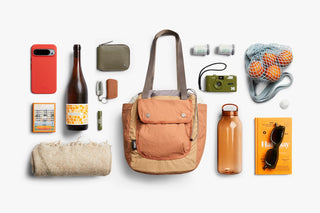 Tan cinch tote flat-lay with travel essentials like bottle and pouches