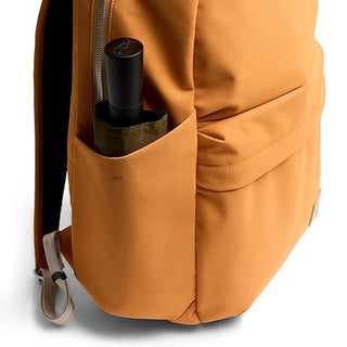 Orange daypack front pocket with bottle-sized organizer slot and visible zipper.