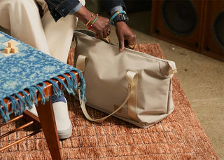 Light tan duffel bag with top handles, set on a rug