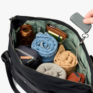 Black zip-top duffel open, showing interior pockets and rolled items