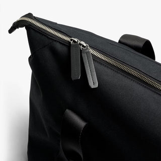 Close-up of black duffel bag with zipper track and front pocket detail.