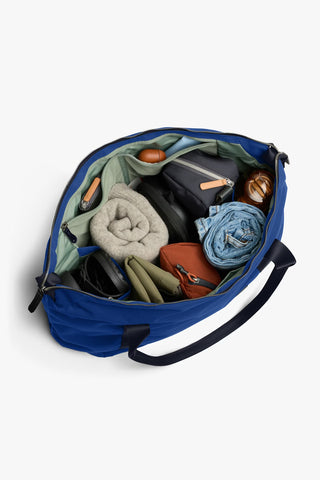Indigo duffel bag open interior with mixed items and green fabric lining