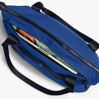 Indigo duffel bag side view with two long zippers and black cross-body strap
