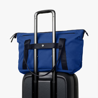 Indigo duffel bag with upright carry handle for stacking on luggage