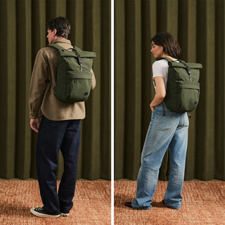 Olive green rolltop backpack worn by a person, front and side straps visible