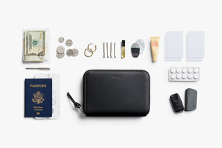 Black zip folio wallet with accessories laid out around it