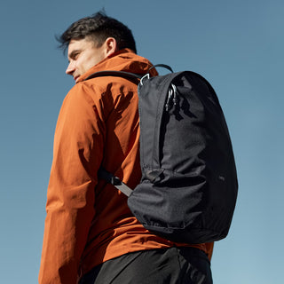 Dark gray daypack carried on a shoulder, with side zipper and padded strap