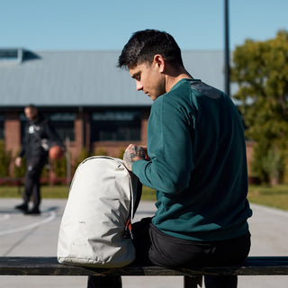 Light gray daypack on a person, showing padded straps and back pocket area