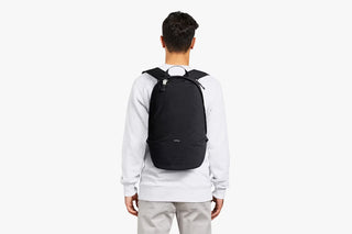 Black daypack worn from behind with adjustable shoulder straps visible