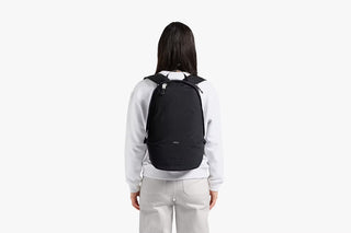 Black daypack worn from behind on a model with padded back straps