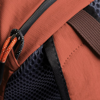 Clay-brown daypack close-up of fabric, black webbing strap, and metal zipper pull