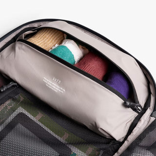 Interior zip pocket inside light gray backpack with fabric lining and “LITE” label