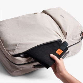 Light gray backpack with top panel zipper and orange logo tag