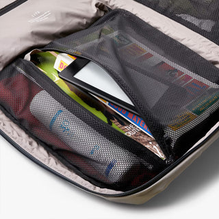 Mesh storage panel inside light gray backpack holding small items in zip pocket