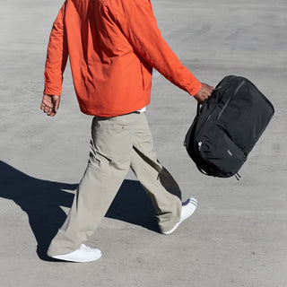 Bellroy Lite Travel Pack 30L Ash backpack, carried by top handle while walking