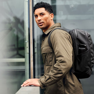 Man wearing a black work backpack with padded straps and front zip pocket