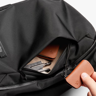 Black backpack interior with zip pocket, elastic pen slots, and brown leather key holder