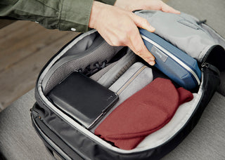 Open black backpack showing gray padded sleeve, mesh organizer, and red zip pouch