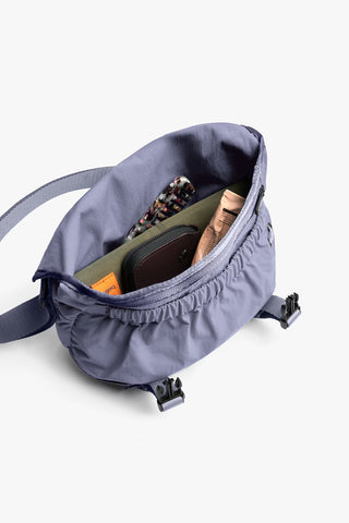 Lilac mini messenger bag opened, showing interior pockets and storage space