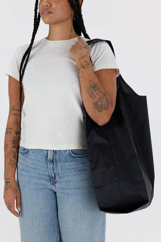 Large black tote bag worn over shoulder, open top with loop handles