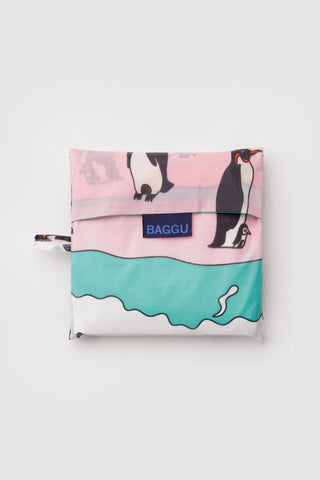 Folded BAGGU penguin-print tote bag with blue logo patch and long zipper strap