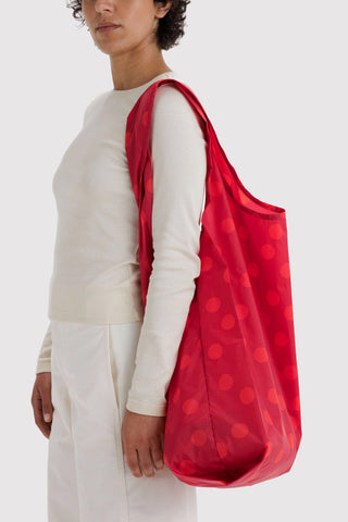 Red polka dot reusable tote bag carried on shoulder with wide straps