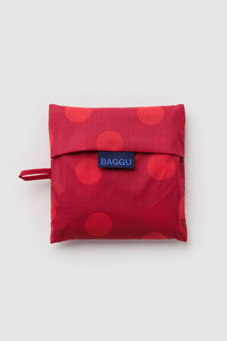 Red polka dot foldable BAGGU pouch with blue logo patch and tie strap