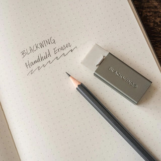 Blackwing handheld eraser with holder on notebook beside pencil