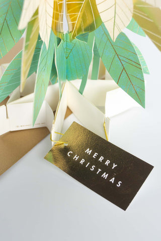 Pop-up Christmas card showing gold-and-green leaves with “MERRY CHRISTMAS” text