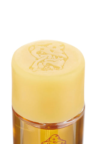Yellow perfume cap with embossed illustration on amber glass bottle