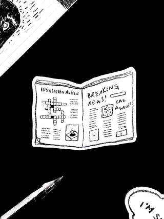 Vinyl sticker shaped like a folded newspaper, black and white with “Breaking News” text