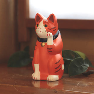 Large orange ceramic fortune cat figurine with blue collar and raised gold bell