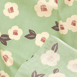 Camellia tenugui close-up: mint green fabric with pale pink blooms and maroon dots