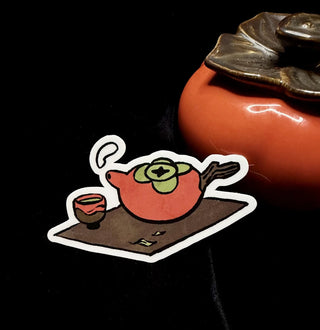 Cartoon teapot vinyl sticker with orange body and green face, white outline