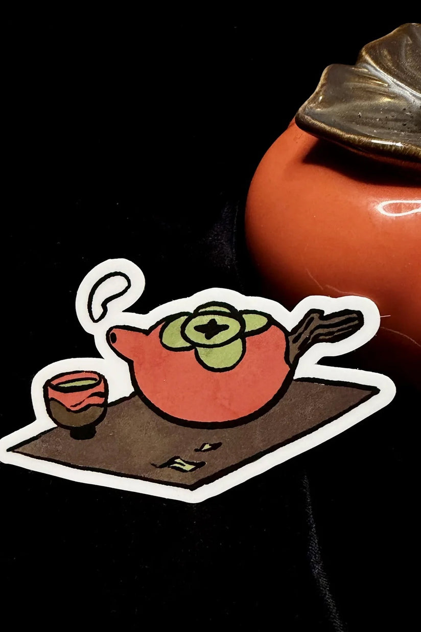 Cartoon teapot vinyl sticker with orange body and green face, white outline