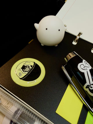 Lime green circular bubble sticker with black character graphic