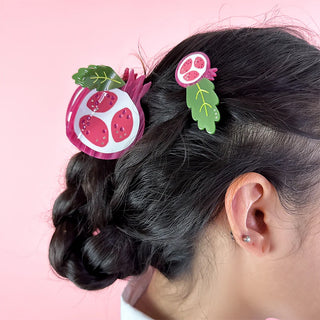 Pomegranate alligator hair clip with maroon fruit and green leaves on dark hair
