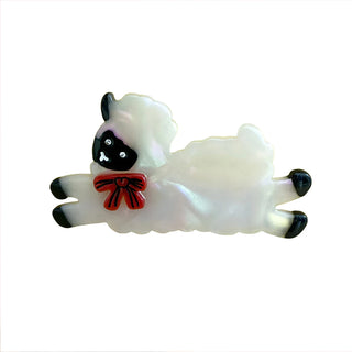 Iridescent sheep hair clip with black face, red bow, and open alligator grips