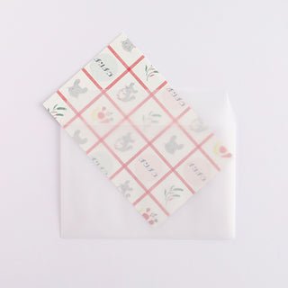 Patterned letter sheet atop a plain white envelope with cat and tulip grid design
