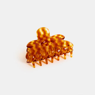 Honey tortoiseshell claw clip with curved flower shape and multiple teeth.