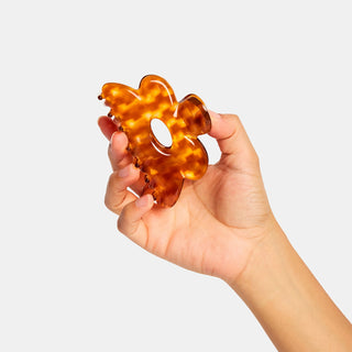 Honey tortoiseshell flower claw hair clip held in hand; scalloped edges.